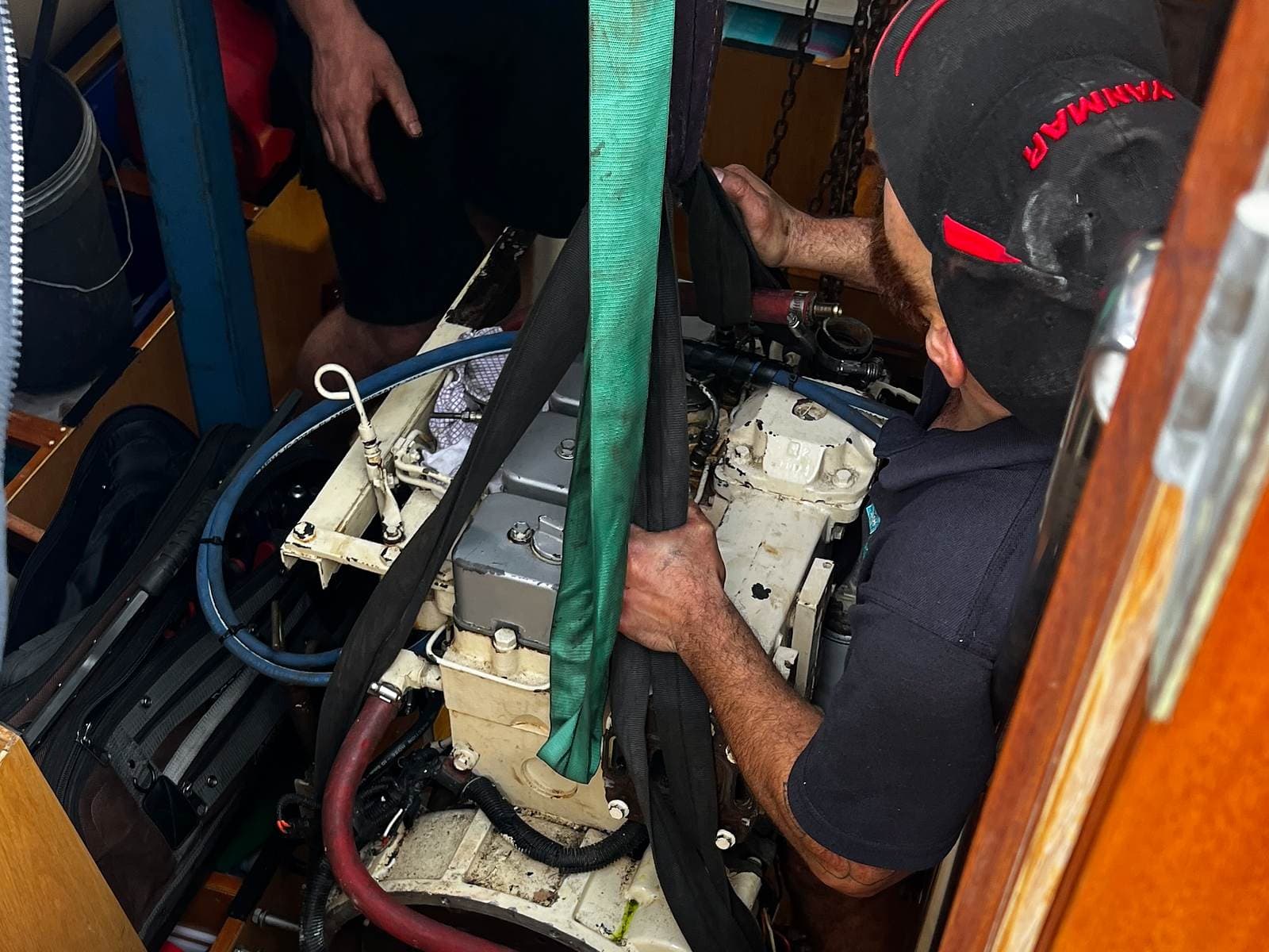 A Mariner Engineering technician guiding an engine into place in a yacht’s engine bay in Williamstown